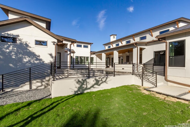 rear view of house featuring stucco siding and a yard