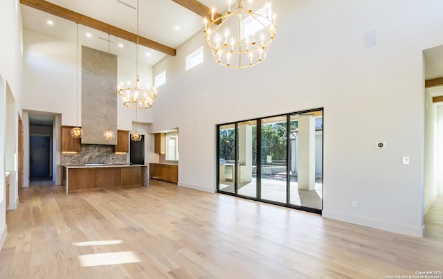 unfurnished living room with light wood-type flooring, baseboards, a chandelier, and beamed ceiling