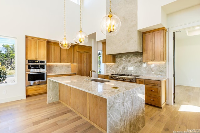 kitchen featuring stainless steel double oven, a sink, a towering ceiling, and light stone countertops