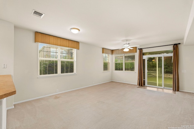 unfurnished room featuring ceiling fan, plenty of natural light, and light carpet