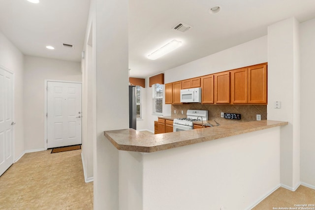 kitchen with white appliances, kitchen peninsula, and tasteful backsplash