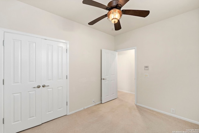 unfurnished bedroom with ceiling fan, a closet, and light carpet