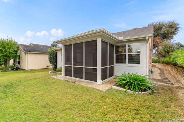 back of house featuring a sunroom and a lawn