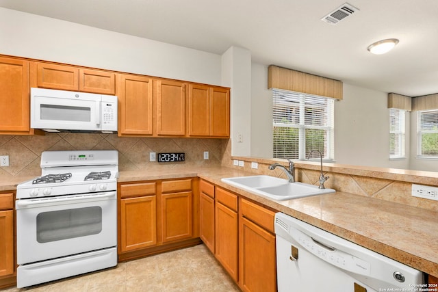 kitchen featuring backsplash, kitchen peninsula, sink, and white appliances