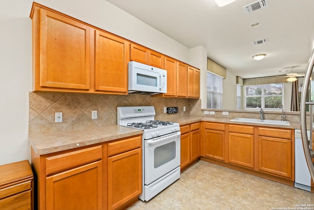 kitchen featuring white appliances, sink, decorative backsplash, ceiling fan, and kitchen peninsula