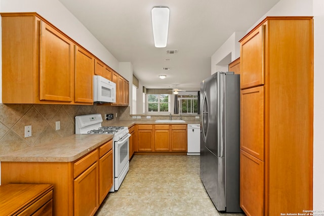 kitchen featuring white appliances, backsplash, and sink