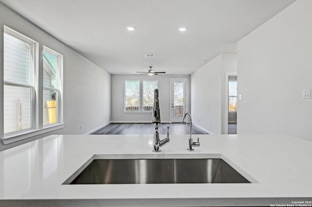 kitchen featuring light countertops, visible vents, open floor plan, a sink, and wood finished floors