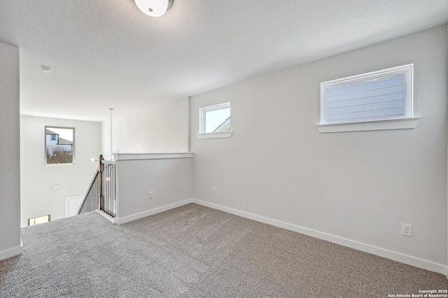 below grade area featuring a textured ceiling, baseboards, and carpet flooring