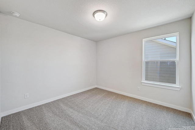 empty room featuring a textured ceiling, baseboards, and carpet flooring