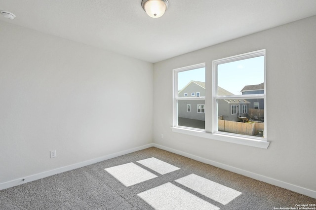 spare room featuring carpet and baseboards