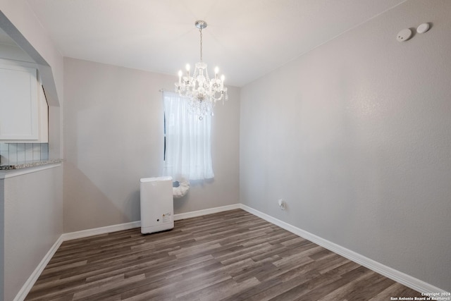 empty room with dark hardwood / wood-style flooring and a notable chandelier