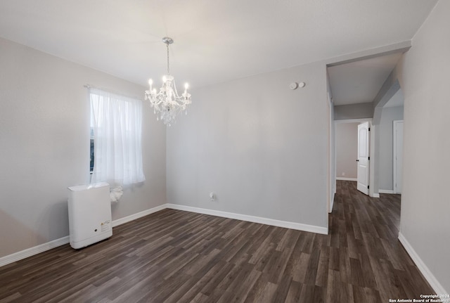 unfurnished room with dark hardwood / wood-style floors and a notable chandelier