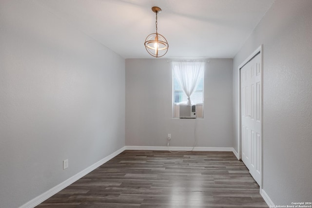 unfurnished bedroom with cooling unit, dark wood-type flooring, and an inviting chandelier