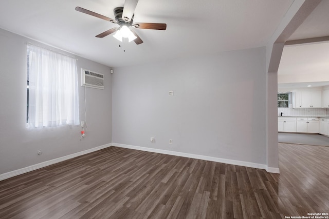 spare room featuring a wall mounted air conditioner, ceiling fan, and dark wood-type flooring