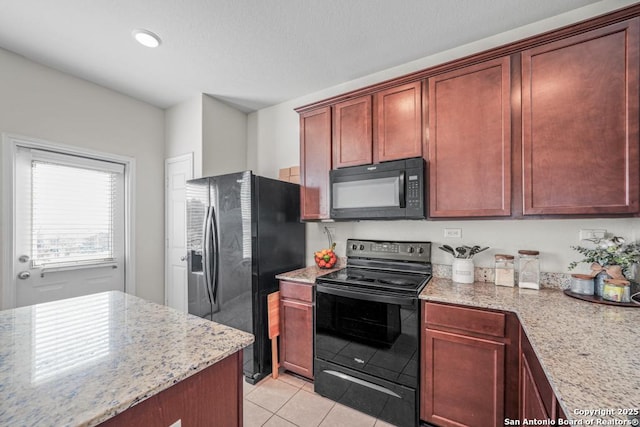 kitchen with light stone counters, black appliances, and light tile patterned flooring