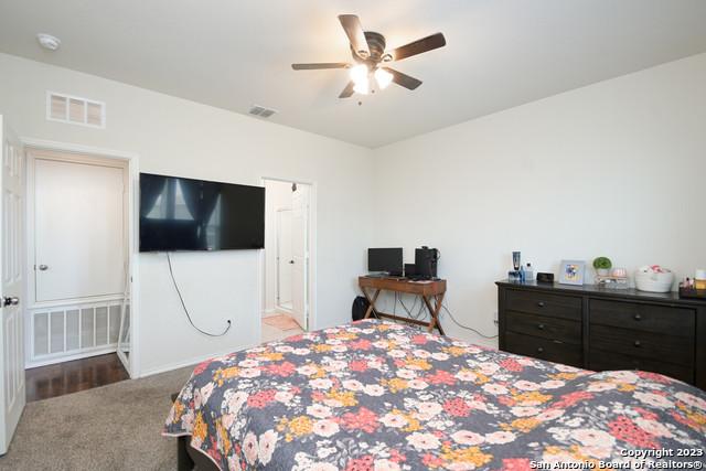 carpeted bedroom with ceiling fan and ensuite bath