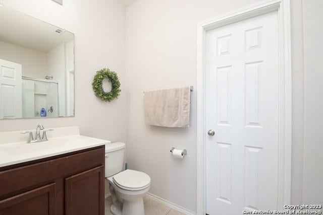 bathroom with tile patterned flooring, vanity, toilet, and walk in shower