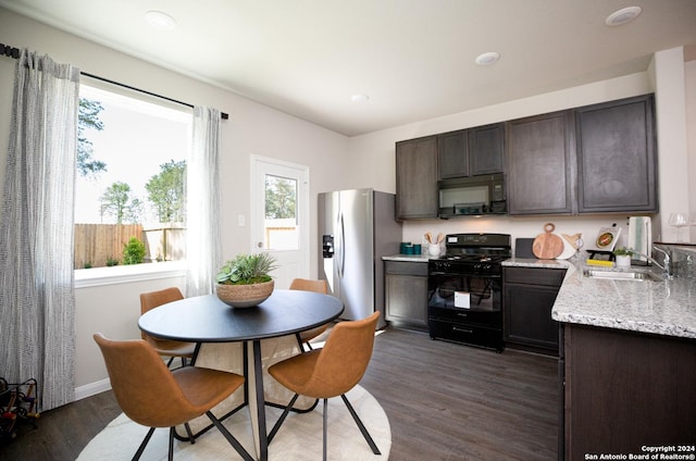 kitchen with black appliances, sink, light stone countertops, dark brown cabinets, and dark hardwood / wood-style flooring