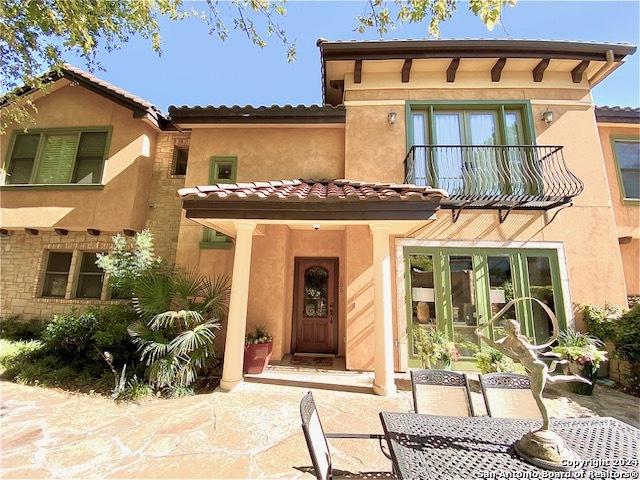 back of property with a balcony and a patio area