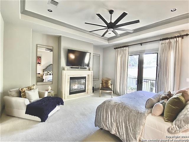 carpeted bedroom featuring access to exterior, ceiling fan, a raised ceiling, and french doors