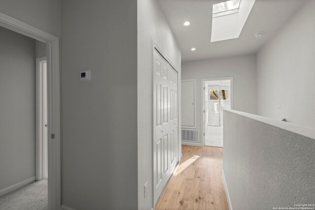 hall with light hardwood / wood-style floors and a skylight