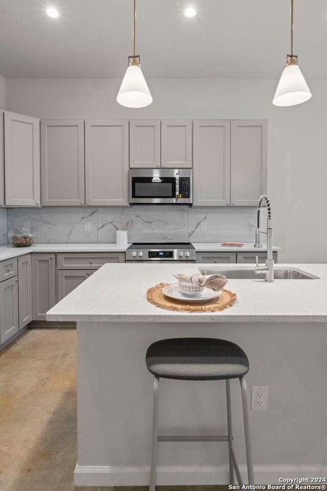 kitchen with gray cabinets, decorative backsplash, hanging light fixtures, and appliances with stainless steel finishes