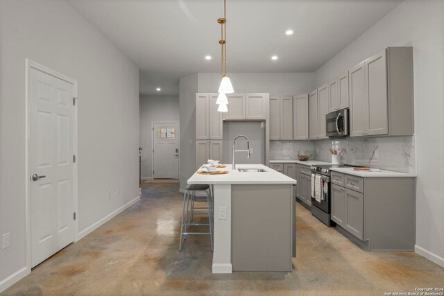 kitchen featuring gray cabinetry, sink, stainless steel appliances, pendant lighting, and a center island with sink