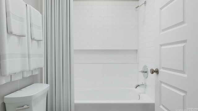 bathroom with tiled shower / bath combo and toilet