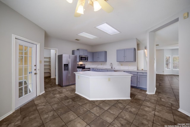 kitchen featuring a center island, sink, ceiling fan, dark tile patterned floors, and stainless steel appliances