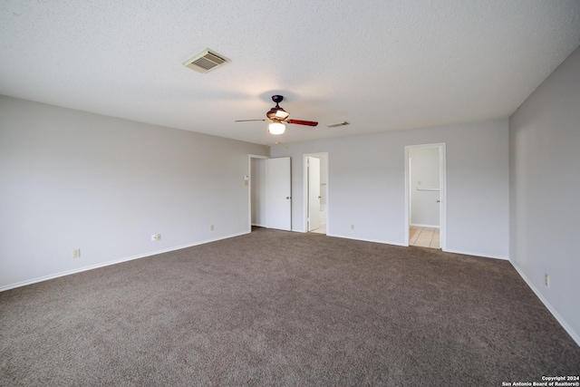 unfurnished bedroom featuring light carpet, a textured ceiling, ceiling fan, and a walk in closet