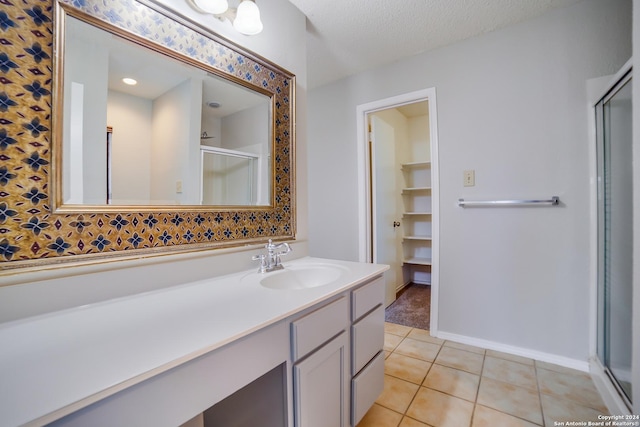 bathroom featuring tile patterned floors, vanity, a shower with shower door, and a textured ceiling