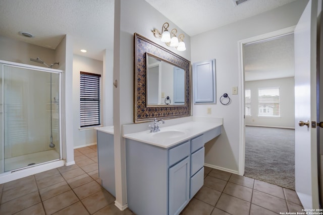 bathroom with vanity, a textured ceiling, tile patterned floors, and a shower with shower door