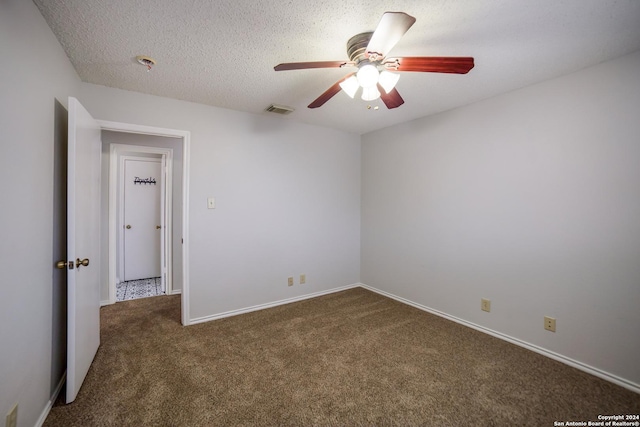 empty room with a textured ceiling, dark carpet, and ceiling fan