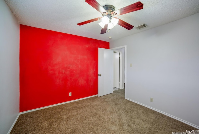 carpeted spare room featuring ceiling fan and a textured ceiling