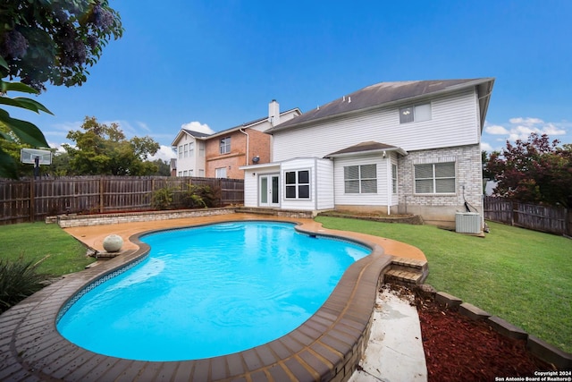 view of pool featuring central air condition unit and a yard