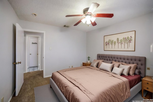 bedroom with dark colored carpet, a textured ceiling, and ceiling fan