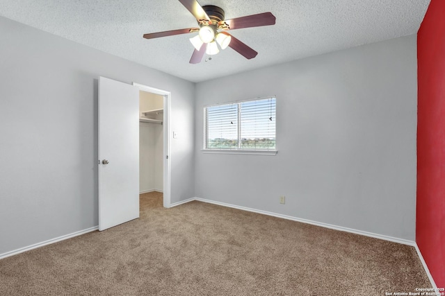 unfurnished bedroom with ceiling fan, carpet, a textured ceiling, a spacious closet, and a closet