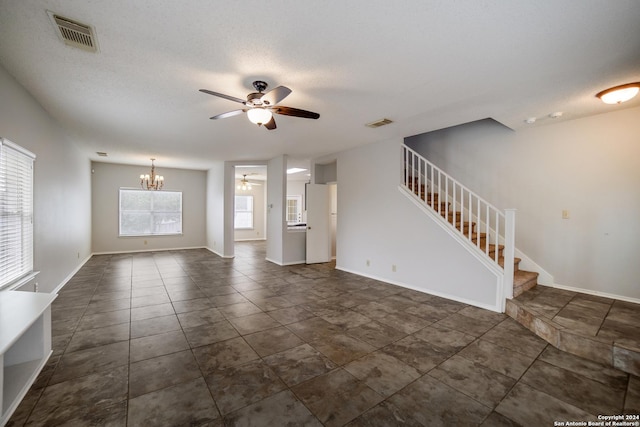 unfurnished living room with a textured ceiling and ceiling fan with notable chandelier