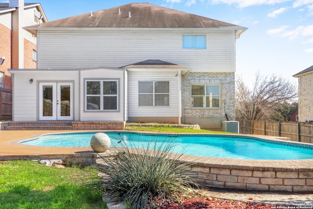 rear view of house with a fenced in pool and french doors