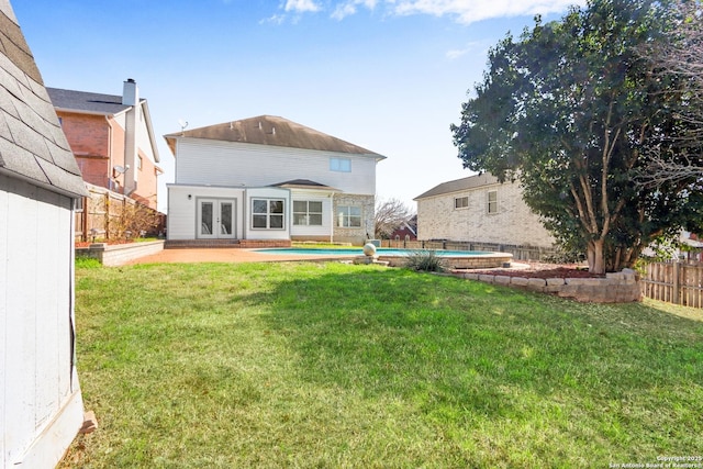 rear view of property with french doors, a patio, a fenced in pool, and a lawn