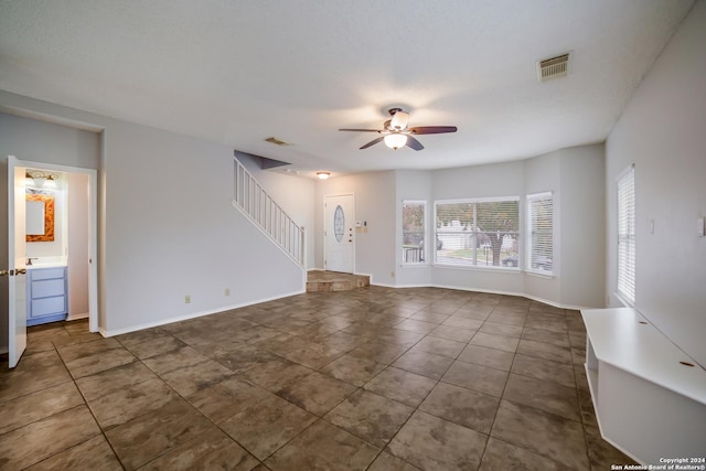 unfurnished living room with dark tile patterned floors and ceiling fan