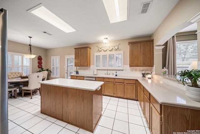 kitchen featuring sink, tasteful backsplash, kitchen peninsula, decorative light fixtures, and light tile patterned floors