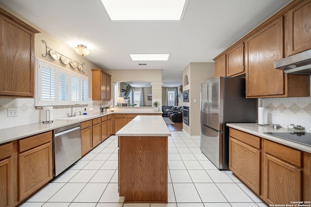 kitchen with light tile patterned flooring, sink, decorative backsplash, appliances with stainless steel finishes, and a kitchen island