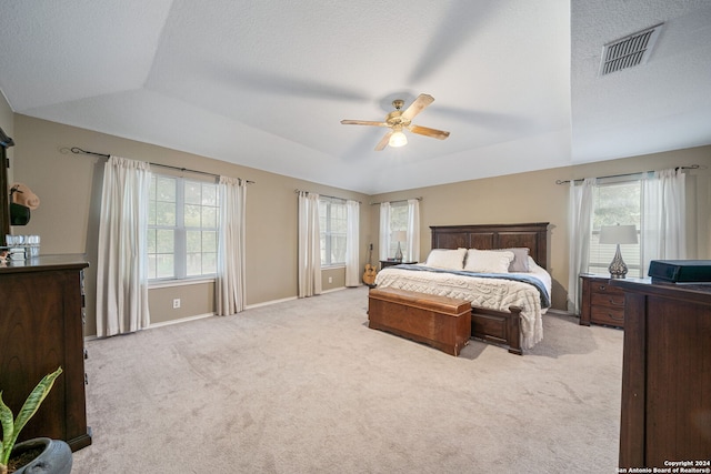 carpeted bedroom with a textured ceiling, a tray ceiling, ceiling fan, and lofted ceiling