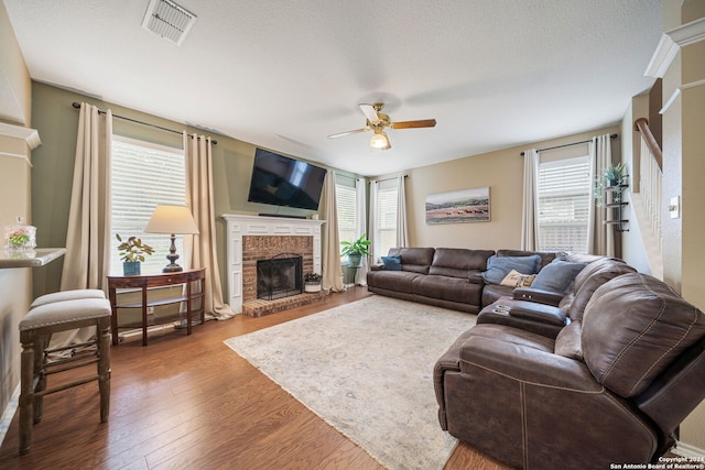 living room featuring a fireplace, wood-type flooring, and a healthy amount of sunlight