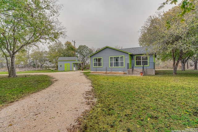 ranch-style house featuring a front lawn and an outdoor structure