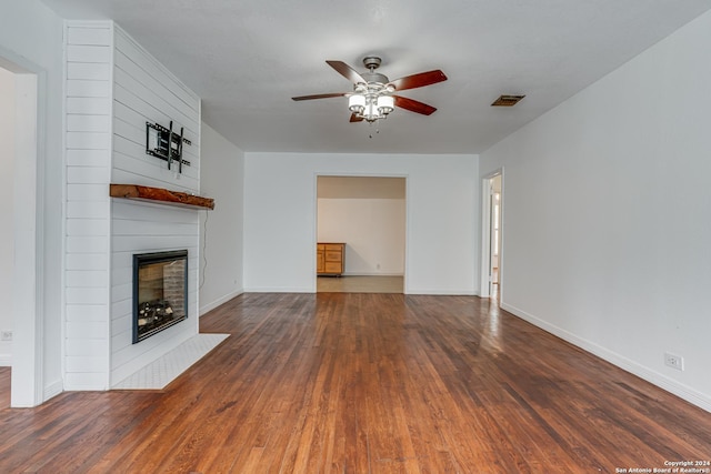 unfurnished living room with a fireplace, dark hardwood / wood-style flooring, and ceiling fan