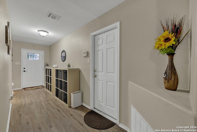 entryway featuring a textured ceiling and light hardwood / wood-style flooring