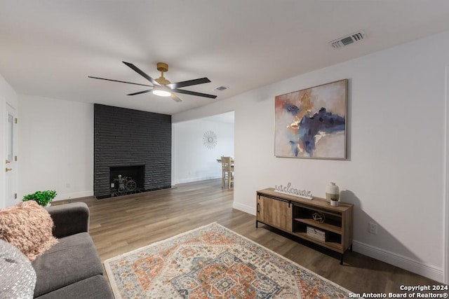 living room with hardwood / wood-style floors, a brick fireplace, and ceiling fan