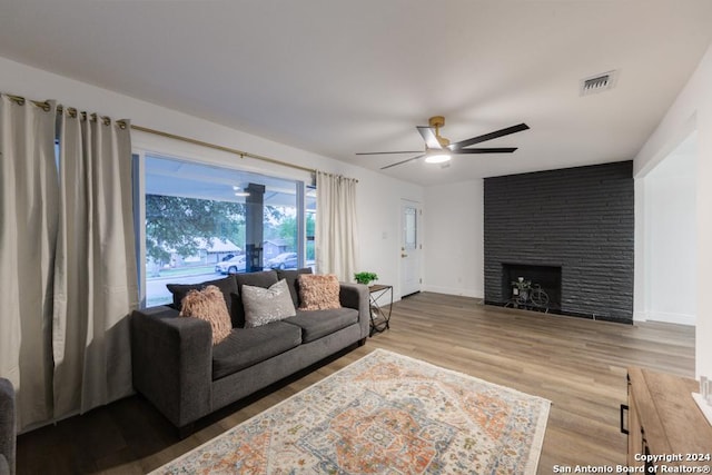 living room with ceiling fan, a fireplace, and hardwood / wood-style flooring